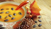 Autumn pumpkin soup with seeps on a wood table